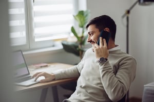 Man smiling on phone and laptop