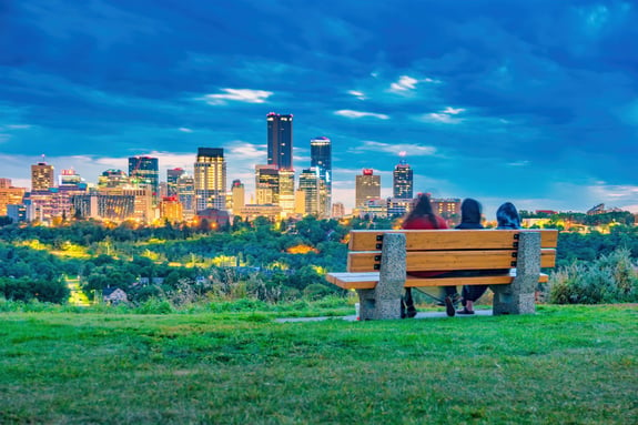 People relax on a park bench with the skyline of downtown Edmonton Alberta Canada