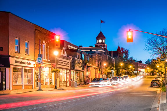 photograph of Main street with illuminated businesses in Downtown Huntsville, Muskoka region, Ontario, Canada, at twilight blue hour.